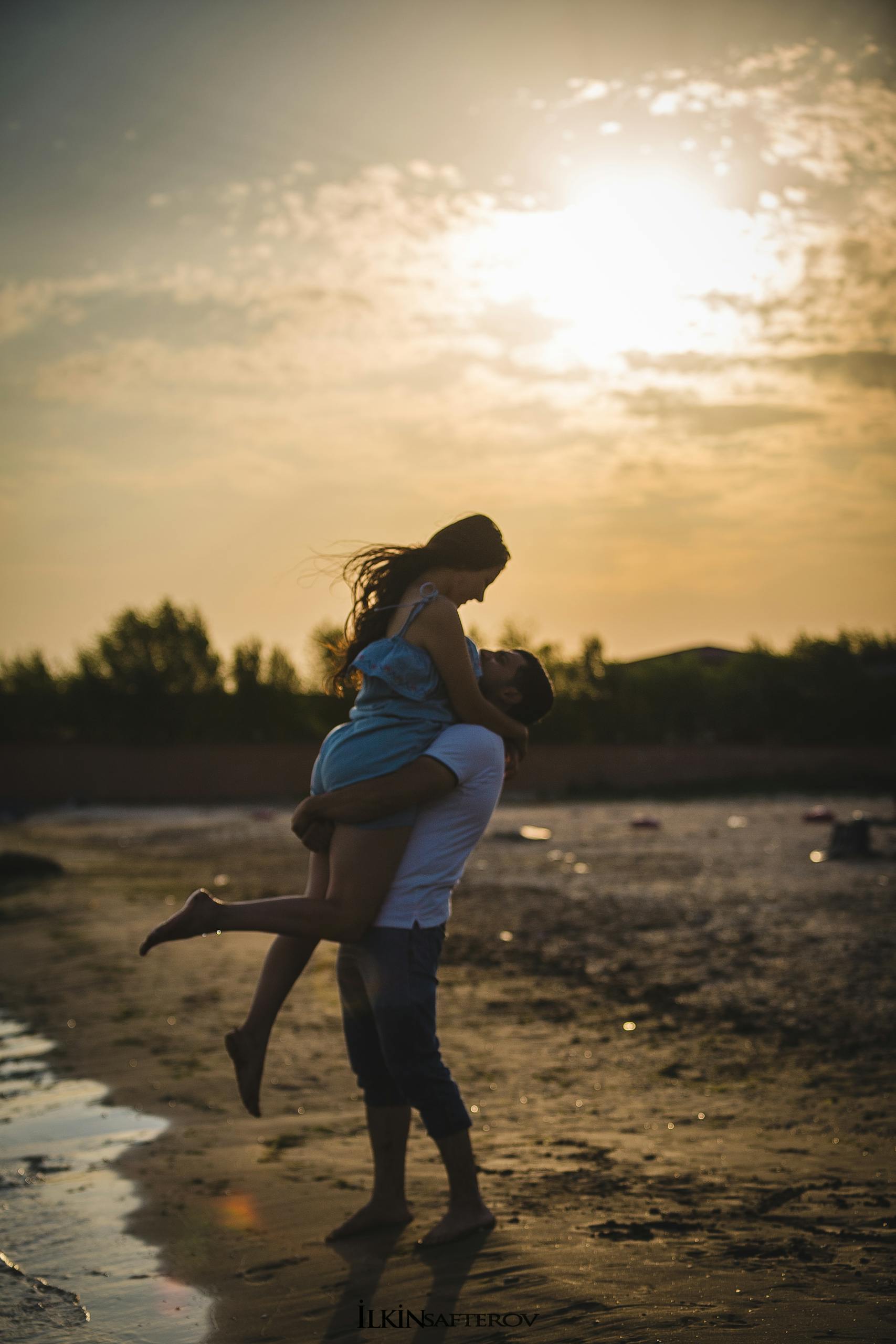 A loving couple embraces during a romantic sunset on a beach in Baku, Azerbaijan.