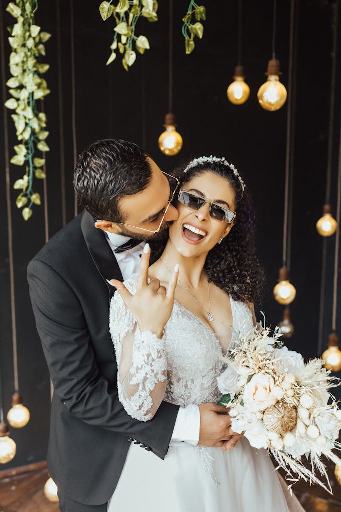 Happy couple celebrating their wedding with smiles, flowers, and hanging lights.